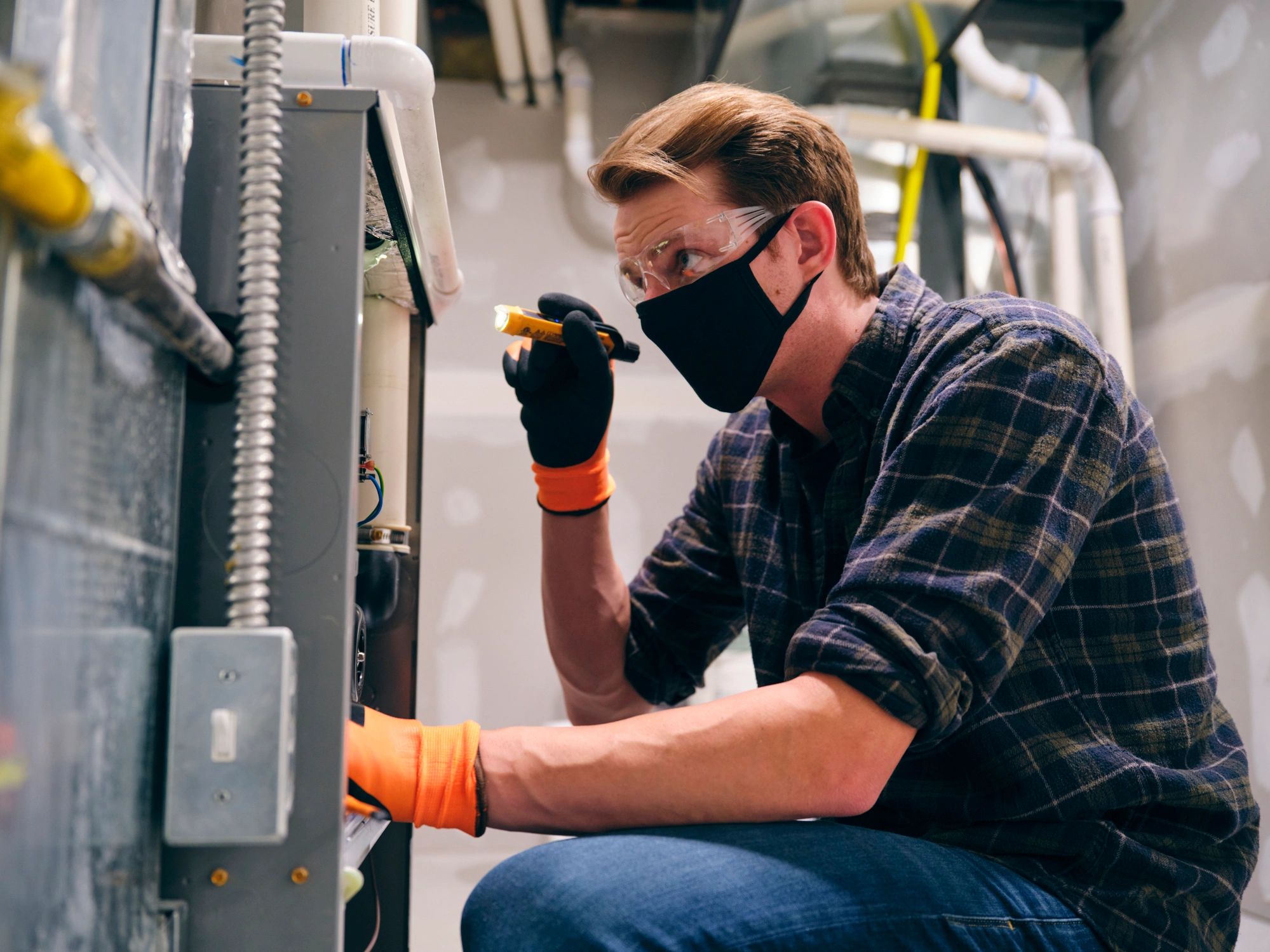 Service technician inspecting HVAC equipment while wearing protective mask