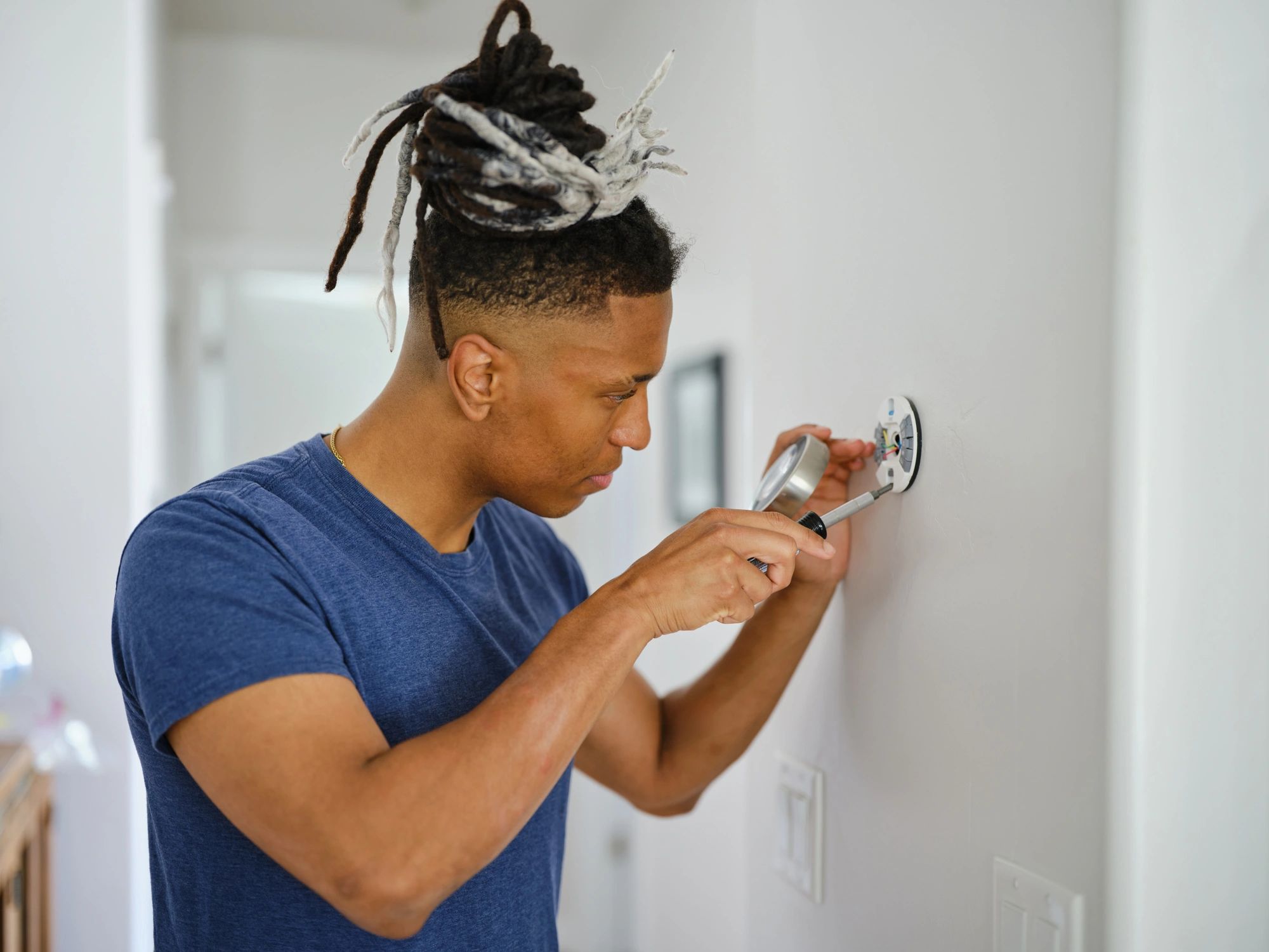 Technician installing a smart thermostat for heating and cooling control